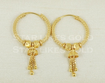 May include: A pair of gold hoop earrings with a dangling charm. The hoops are made of a woven metal and the charms are shaped like bells with a chain tassel.