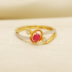 May include: A gold ring featuring a red gemstone and small white gemstones set in a delicate, swirling design.