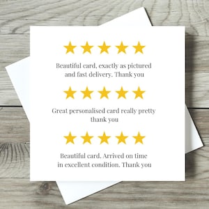 May include: A white greeting card with text and yellow star ratings. The text includes phrases like "Beautiful card" and "fast delivery." The card is on a wooden surface.