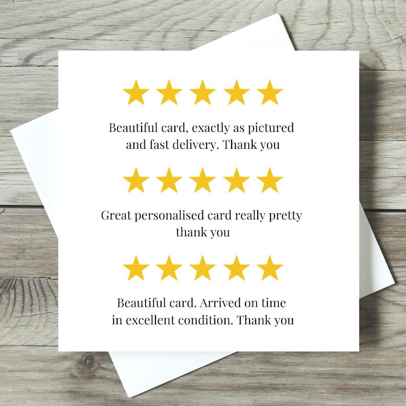 May include: A white greeting card with text and yellow star ratings. The text includes phrases like "Beautiful card" and "fast delivery." The card is on a wooden surface.