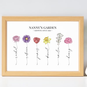 May include: A white framed print with the text "Nanny's Garden - Growing Since 1990 -" and a line of flowers with names written underneath each flower. The flowers are a purple chrysanthemum, a purple aster, a red rose, a yellow daffodil, a white lily of the valley, and a pink carnation. The names are Rachel, Rebecca, James, Daniel, Emilia, and Henry.