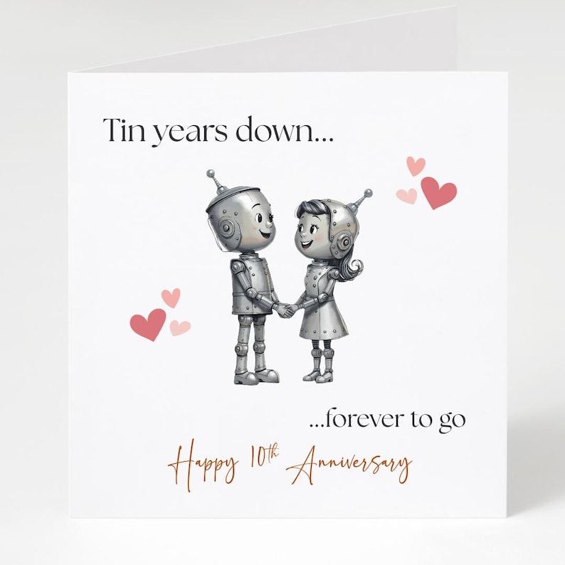 May include: A white greeting card with the text "Tin years down... ...forever to go Happy 10th Anniversary." The card features two robot figures holding hands, with pink hearts scattered around them.