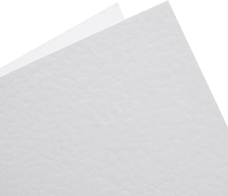 May include: A close-up of two white sheets of paper with a textured surface. The sheets are angled, revealing a corner and the edges of the paper against a white background.