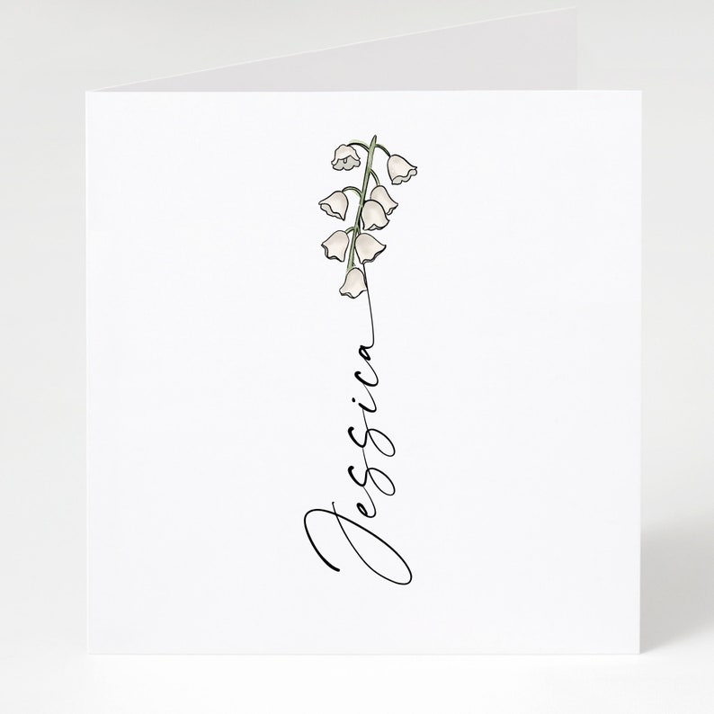 May include: A white card with a simple line drawing of a lily of the valley flower and the name "Jessica" written in cursive.
