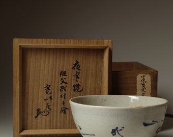 May include: A white ceramic teacup with blue brushstrokes and a wooden box with Japanese characters. The box has the text "松楽庵" and "福田宗明"