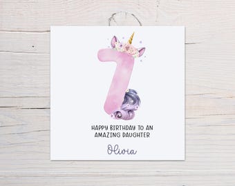 May include: A pink unicorn-shaped number seven with a purple flower crown and a purple tail. The card says "Happy Birthday to an Amazing Daughter Olivia".