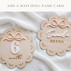 Adorned with a dainty bow milestone, it symbolizes the journey of the baby girl's first year, marked with love and care.