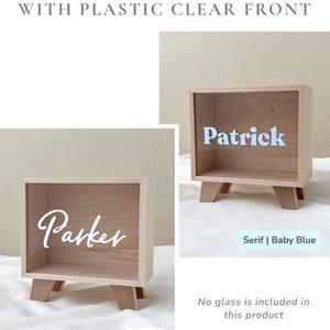 May include: Two rectangular wooden shadow boxes made from finished maple with a clear plastic front. One box features the name Patrick in light blue letters, and the other features the name Parker in white letters. Both boxes stand on four legs.