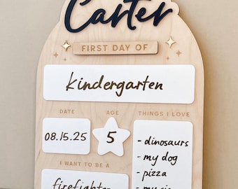 May include: Wooden first day of kindergarten sign with the name "Carter" in black script. The sign includes sections for date, age (5), and things I love, including dinosaurs, my dog, pizza, and my sis. The sign also states "I want to be a firefighter."