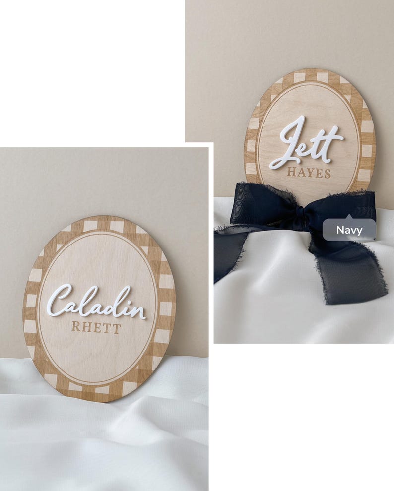 K&ouml;nnte beinhalten: Zwei ovale Holzschilder mit einem hellbraunen Karomuster am Rand. Ein Schild zeigt den wei&szlig;en 3D-Schriftzug Caladin und den braunen Text RHETT. Das andere Schild zeigt den wei&szlig;en 3D-Schriftzug Jett und braunen Text HAYES mit einer marineblauen Schleife.