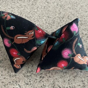 May include: Two black triangular fabric pillows with a repeating pattern of brown squirrels and pink, red, and blue Christmas lights.