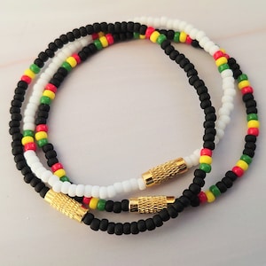 May include: Three beaded bracelets with black, white, red and green beads. The bracelets have gold metal clasps.