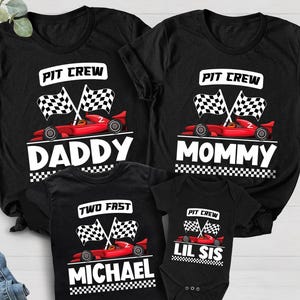May include: Black t-shirts and a onesie with racing car graphics. The shirts say "Pit Crew" with "Daddy", "Mommy", "Michael", and "Lil Sis" below the car design. The shirts have checkered flags and a red race car.