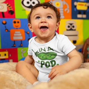 May include: A white baby onesie with a green pea pod design and the text "In a Pod."