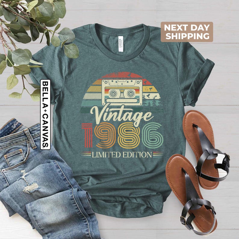 May include: Teal t-shirt with a retro design featuring a cassette tape, a sunset, and the text "Vintage 1986 Limited Edition." The shirt is paired with blue jeans and brown sandals.
