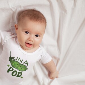 May include: A white baby onesie with a green pea pod graphic and the text "In a Pod."