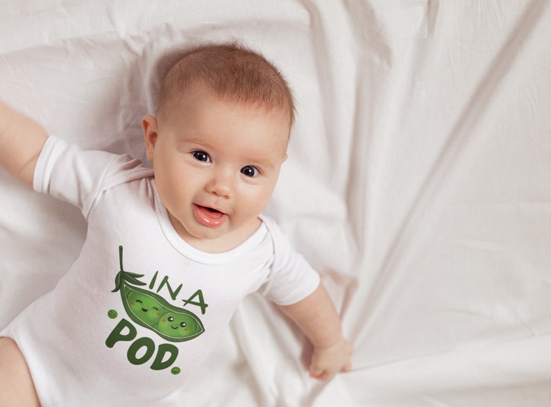 May include: A white baby onesie with a green pea pod graphic and the text "In a Pod."