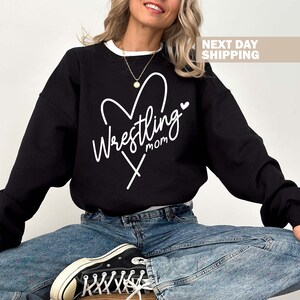 May include: Black sweatshirt with a white heart design and the text "Wrestling Mom" inside the heart.