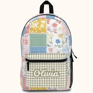 May include: A colorful patchwork backpack with a black top handle and zipper. The backpack features a variety of floral and gingham patterns in pastel colors. The name "Olivia" is printed on the front pocket.