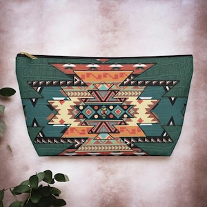 May include: A rectangular cosmetic bag with a Southwestern geometric pattern in shades of orange, teal, and cream. The bag has a green textured top and a gold zipper.