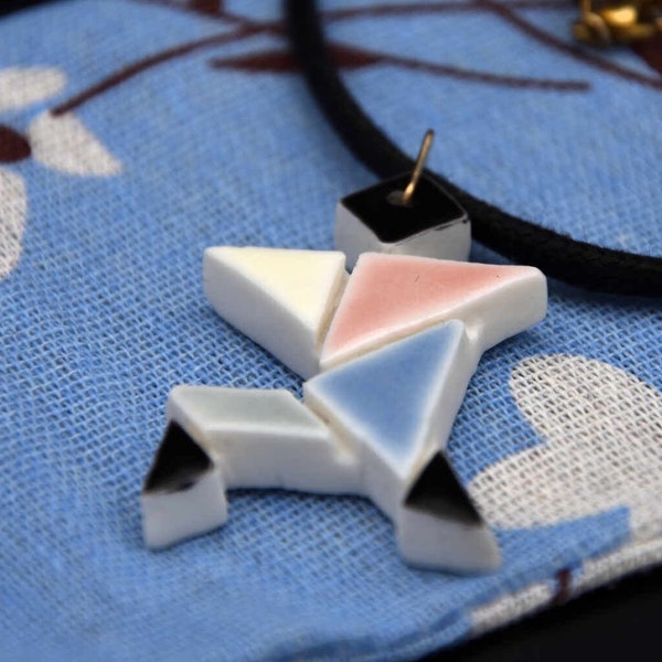 Pendentif tangram en porcelaine blanche avec émail bleu, rose, jaune, noir et gris. Collier en céramique, fait à la main. Bijou artisanal.