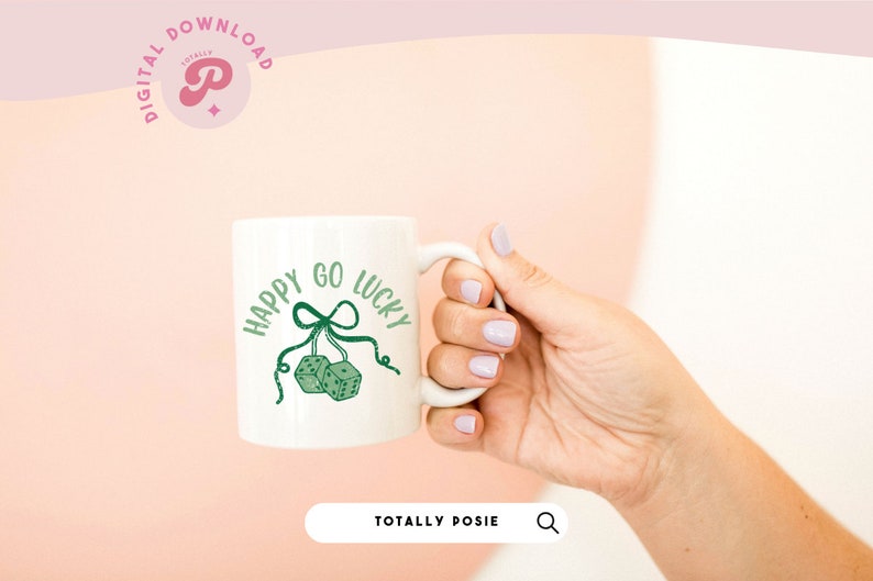 Puede incluir: Taza de cer&aacute;mica blanca con un dise&ntilde;o verde que dice "Happy Go Lucky" con dos dados verdes colgando de una cinta verde.