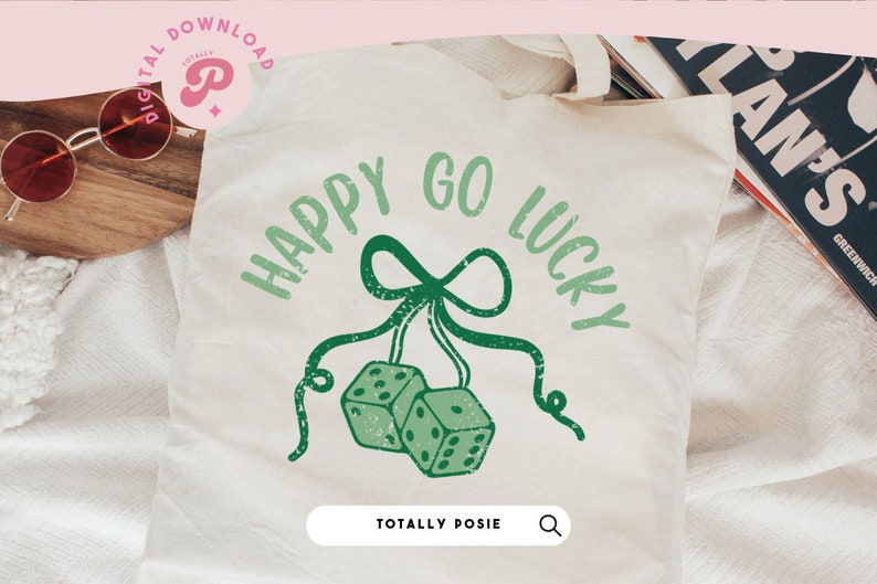 Puede incluir: Una bolsa de tela blanca con el texto "Happy Go Lucky" en verde y un lazo verde con dos dados verdes colgando de &eacute;l. El texto "Totally Posie" est&aacute; en la parte inferior de la bolsa.