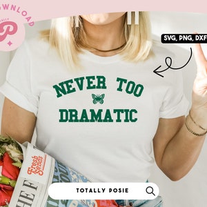 May include: White t-shirt with green text that reads "NEVER TOO DRAMATIC" with a green butterfly graphic. The text is in a collegiate font.