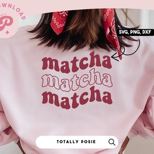 May include: A pink sweatshirt with the words "matcha matcha matcha" in a retro font printed on the back. The text is in a burgundy color.