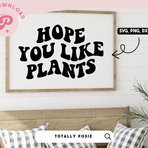 May include: A framed print with the text "HOPE YOU LIKE PLANTS" in a retro font style. The print is hanging on a white wall with wood paneling.