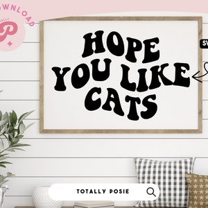 May include: A framed print with the text "HOPE YOU LIKE CATS" in a retro font style. The text is in black on a white background. The frame is brown wood.