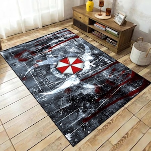 May include: A black and white rug with a red biohazard symbol and the words "Umbrella Corporation" in white. The rug has a distressed, grunge-like appearance.