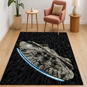 Puede incluir: Una alfombra de área negra y gris con un diseño de nave espacial. La nave espacial está volando a través de un campo de estrellas. La alfombra es perfecta para un fanático de Star Wars.