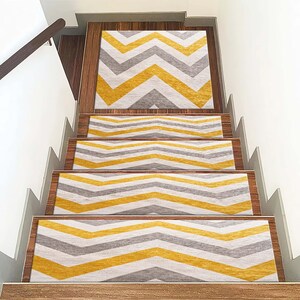 Puede incluir: Conjunto de cinco peldaños de escalera con un patrón de chevron en amarillo y gris. Los peldaños están diseñados para agregar un toque decorativo a las escaleras y proporcionar una superficie antideslizante.