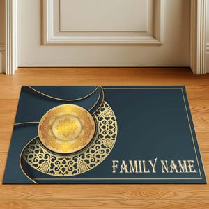 Può includere: Un zerbino rettangolare con sfondo blu navy e un design decorativo dorato. Il design include un emblema circolare e una forma a mezzaluna con motivi intricati. Le parole "FAMILY NAME" sono stampate in oro.