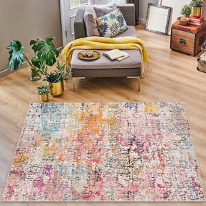 May include: A colorful abstract area rug with shades of pink, orange, blue, and yellow. The rug has a distressed, vintage look.