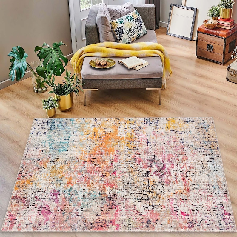 May include: A colorful abstract area rug with shades of pink, orange, blue, and yellow. The rug has a distressed, vintage look.
