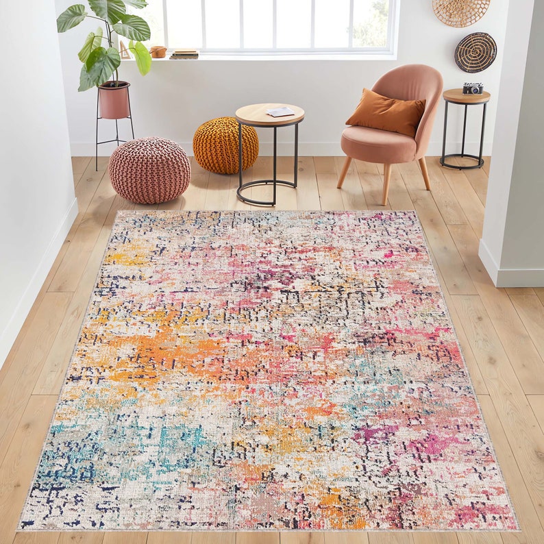 May include: A colorful abstract area rug with shades of pink, yellow, blue, and white. The rug has a distressed, vintage look.
