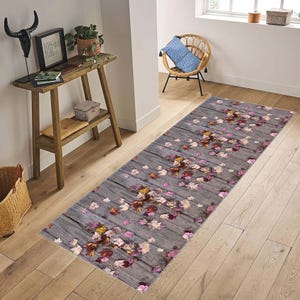 May include: A gray and pink runner rug with a woodgrain pattern and scattered autumn leaves. The rug has a floral design with pink, yellow, and brown leaves.