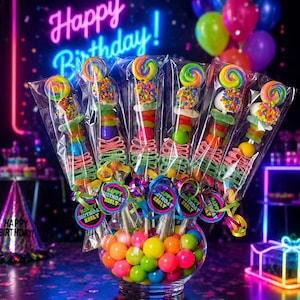 May include: Six candy skewers in clear plastic wrappers, each topped with a colorful swirl lollipop and assorted gummy candies, arranged in a glass bowl filled with bright gumballs. Each skewer features a round tag reading Happy Birthday Keely.