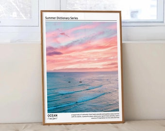 May include: A framed print with a summer dictionary series title. The print features a photograph of a pink and orange sunset over a blue ocean with waves. The text "OCEAN /ˈoʊʃən/" is at the bottom of the print.