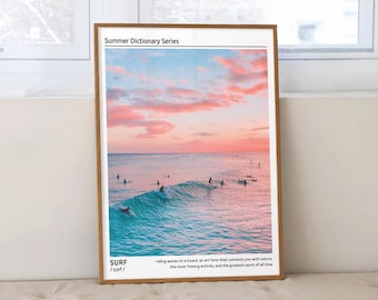 May include: A framed print with a summer dictionary series theme. The print features a photograph of surfers riding waves in the ocean at sunset. The sky is a vibrant pink and orange, and the water is a turquoise blue. The text on the print reads "SURF /sarf/ riding waves on a board an art form that connects you with nature, the most freeing activity, and the greatest sport of all time."