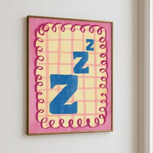 Puede incluir: Una impresión artística enmarcada con un borde rosa y un diseño rizado. La obra de arte muestra un fondo de cuadrícula amarilla con tres letras azules "Z", lo que sugiere el sueño. El marco es dorado.
