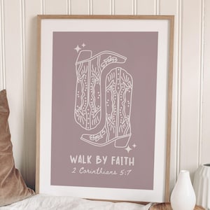 May include: A framed print featuring a line drawing of cowboy boots in white on a mauve background. The text "WALK BY FAITH" and "2 Corinthians 5:7" are below the boots. The print is displayed near a pillow and decorative vases.