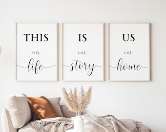May include: Three black and white framed prints with the text "This is our life", "This is our story", and "This is our home". The prints are hanging on a white wall above a beige couch.