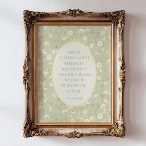 Op de afbeelding: Een sierlijke, goudomrandde print met een lichtgroene achtergrond bedekt met kleine witte en gele bloemen. De print bevat een ovaal met de tekst "SHE IS CLOTHED WITH STRENGTH AND DIGNITY. AND SHE LAUGHS WITHOUT FEAR OF THE FUTURE" en "Proverbs 31:25".