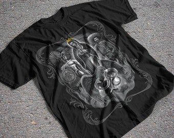 May include: Black t-shirt with a white graphic print of a woman with a crown, a man with a hat, and a snake. The graphic is surrounded by a decorative border.