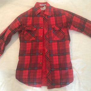 May include: A red and black plaid flannel shirt with a button-up front and two chest pockets.