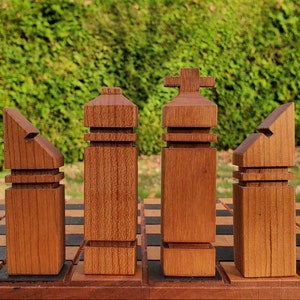 May include: A set of wooden chess pieces with a modern, abstract design. The pieces are made of a light brown wood and have a smooth finish. The pieces are arranged on a chessboard, with the white pieces on the left and the black pieces on the right.