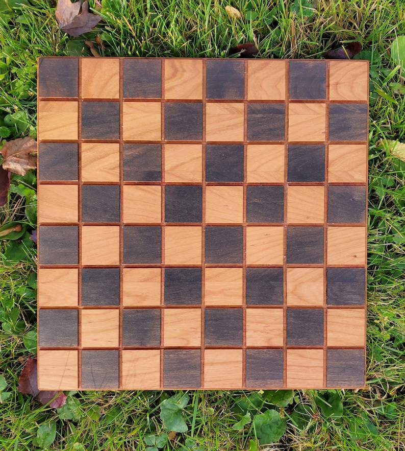 May include: A wooden checkerboard with a dark brown and light wood pattern. The board has 64 squares arranged in an 8x8 grid.